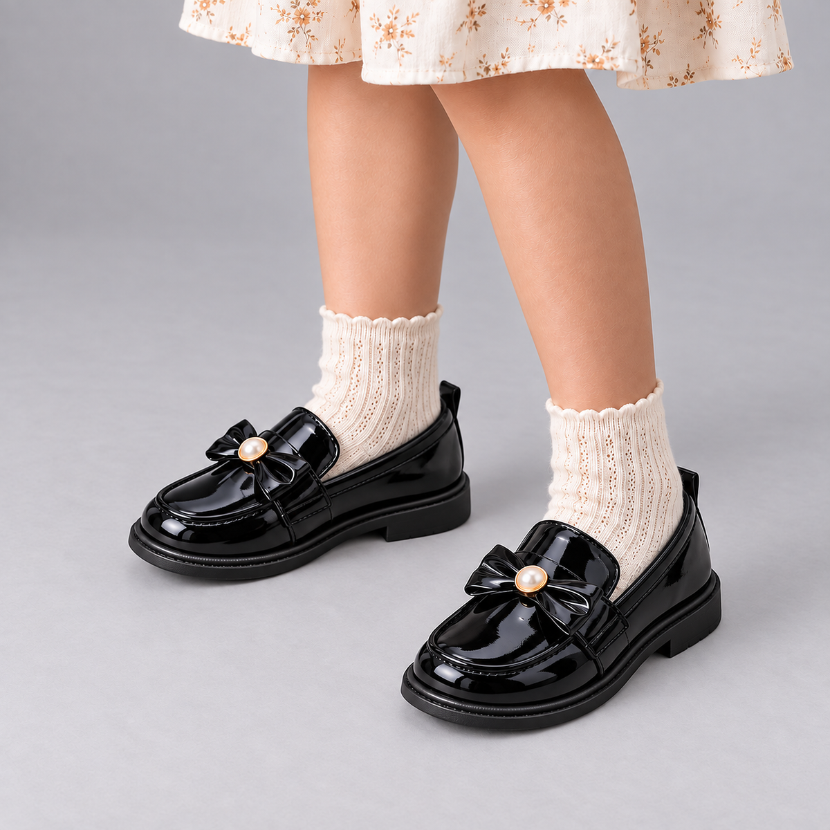 Girl wearing Kids Patent Bow Loafers with cream socks in premium studio photo