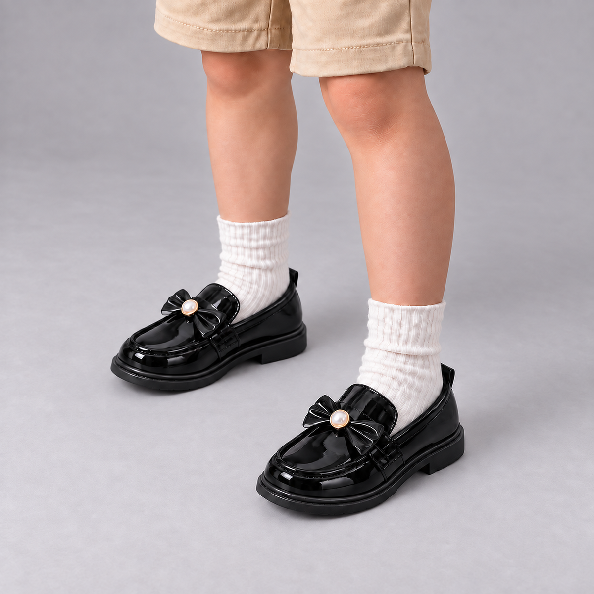Boy wearing Kids Patent Bow Loafers with cream socks in premium studio photo